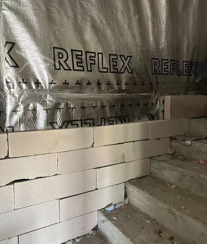 White masonry lining under construction in front of the membrane-covered VIP layer.