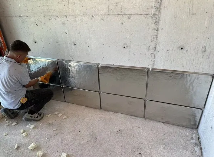 Installer positioning a stainless steel VIP at the base of an internal wall.